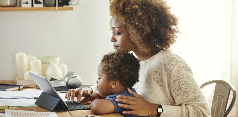 Mother working on tablet computer while her child is watching