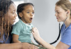 Nurse using stethoscope on child