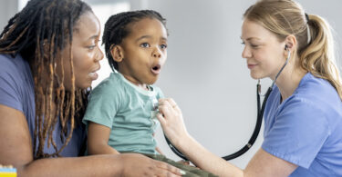 Nurse using stethoscope on child