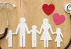 Paper cut-outs of family with a stethoscope and two paper cut-out hearts framing the family