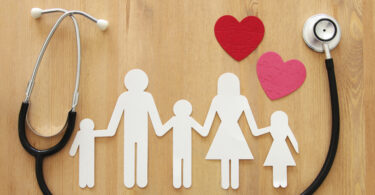 Paper cut-outs of family with a stethoscope and two paper cut-out hearts framing the family