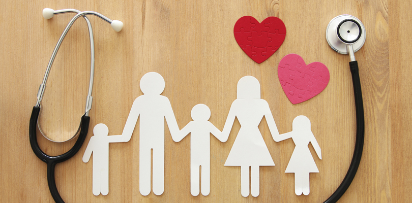 Paper cut-outs of family with a stethoscope and two paper cut-out hearts framing the family